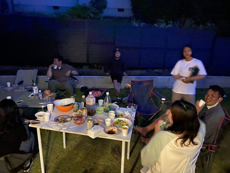 夜の庭で、テーブルを囲んで座っている人たち