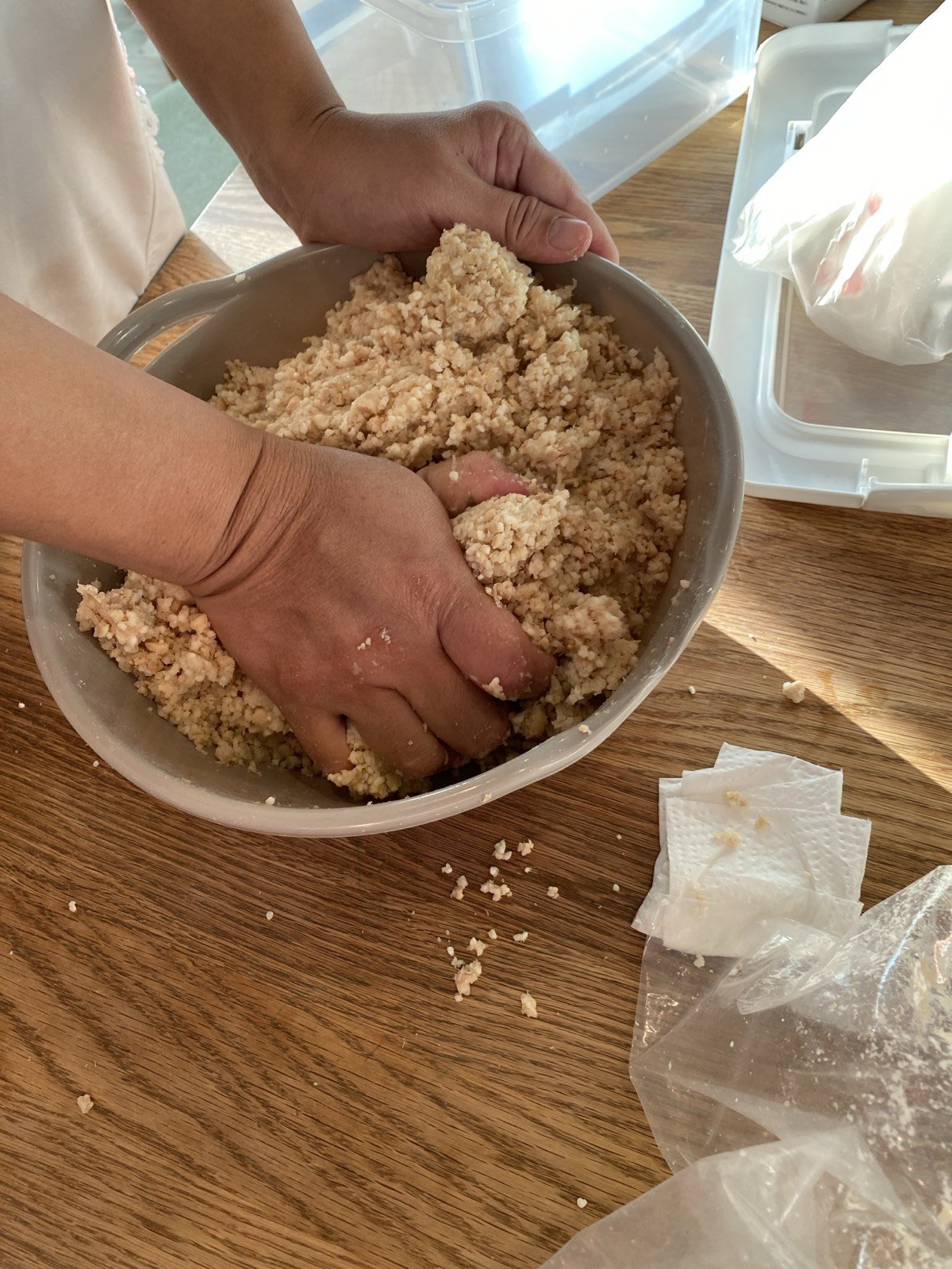 ボウルの中で、つぶした大豆と麹を手で混ぜているところ