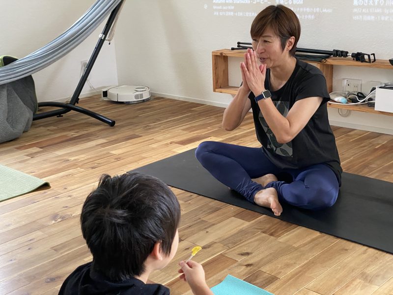 朝のリビングでヨガをする人と、それを見る子どもの写真